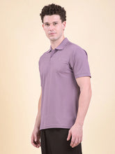 Man wearing a purple polo t-shirt (DCYPHR Men's Element Polo - Dusk Plum) against a beige background, facing sideways.